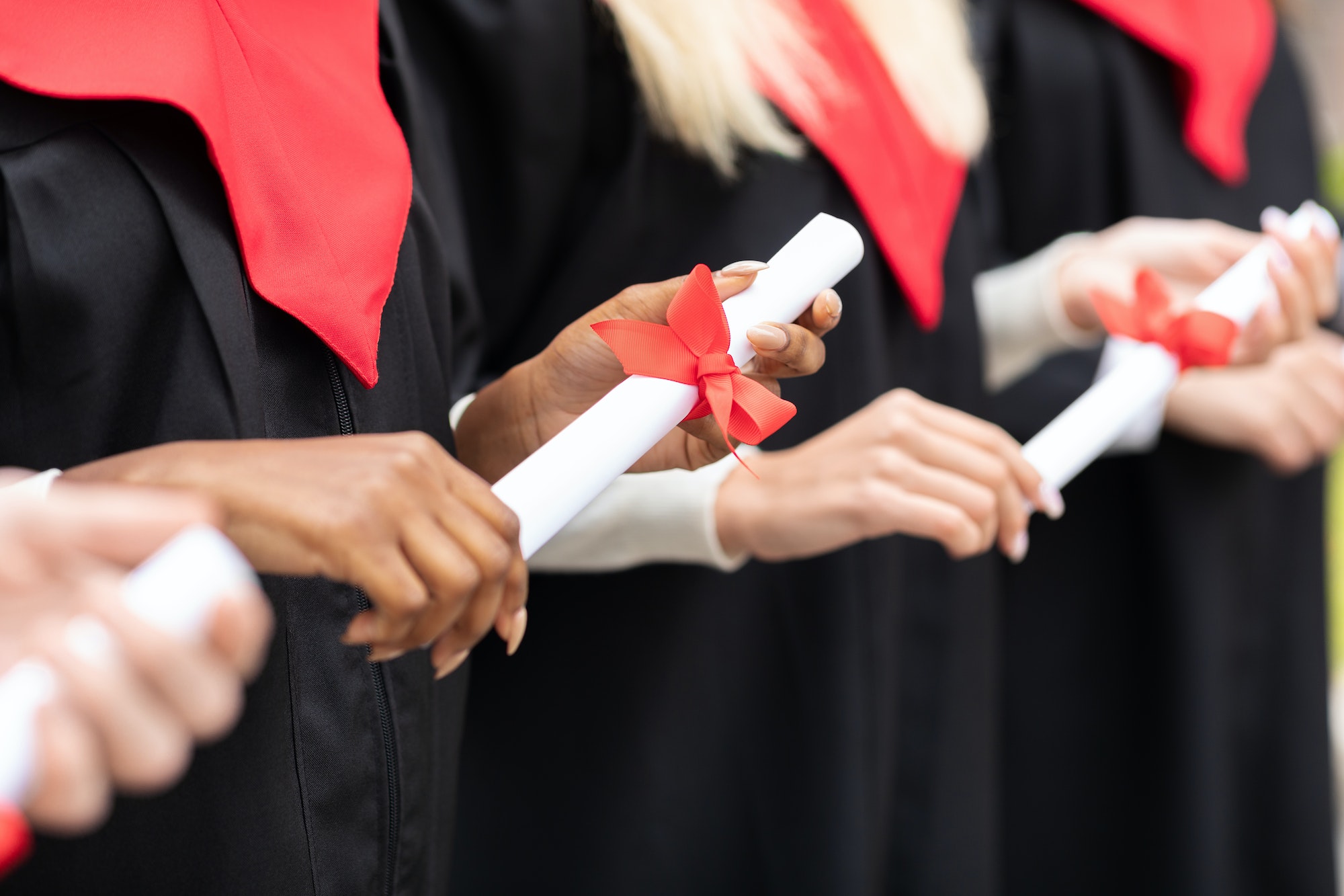 Unrecognizable multiracial group of graduates holding diplomas